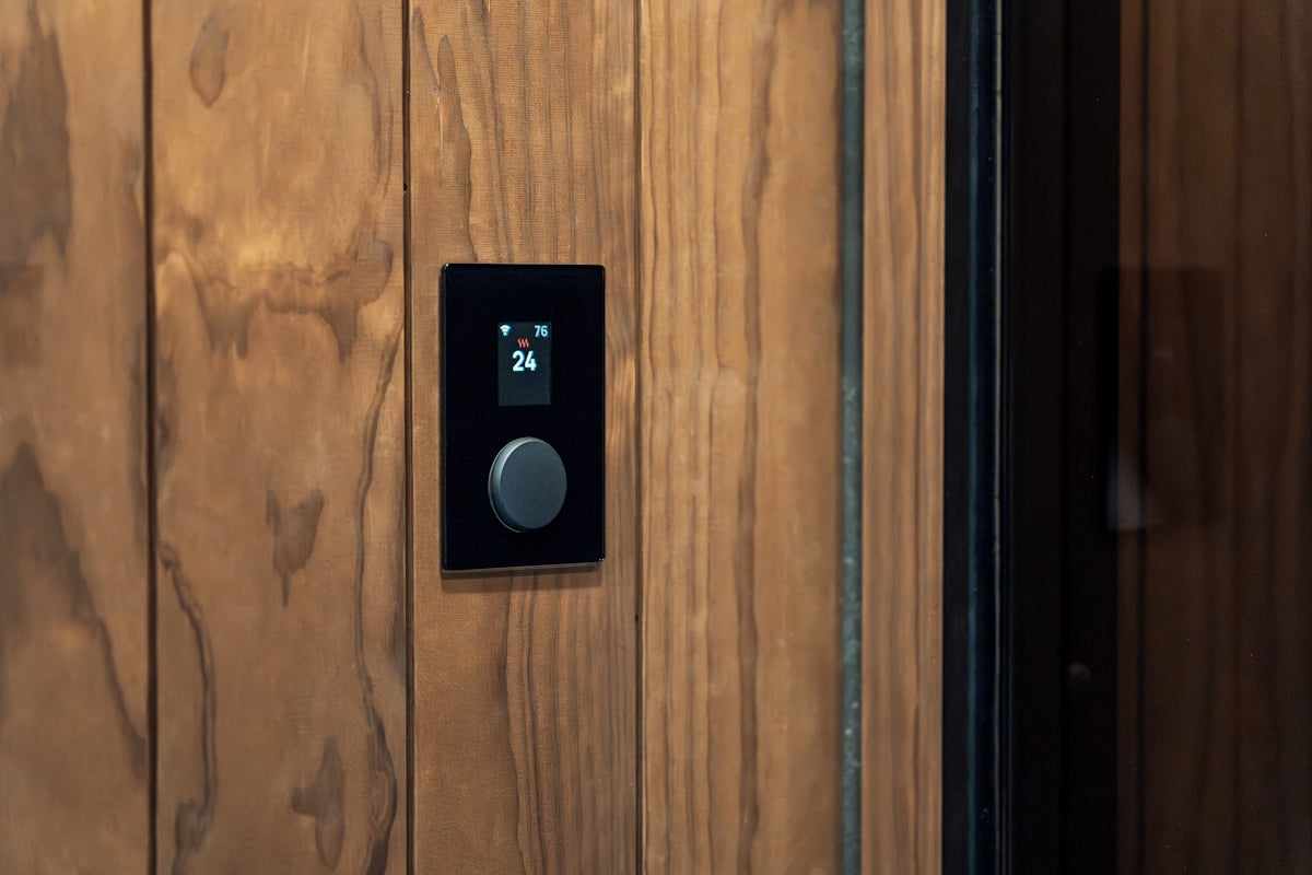 Modern black control panel with a knob on wood.