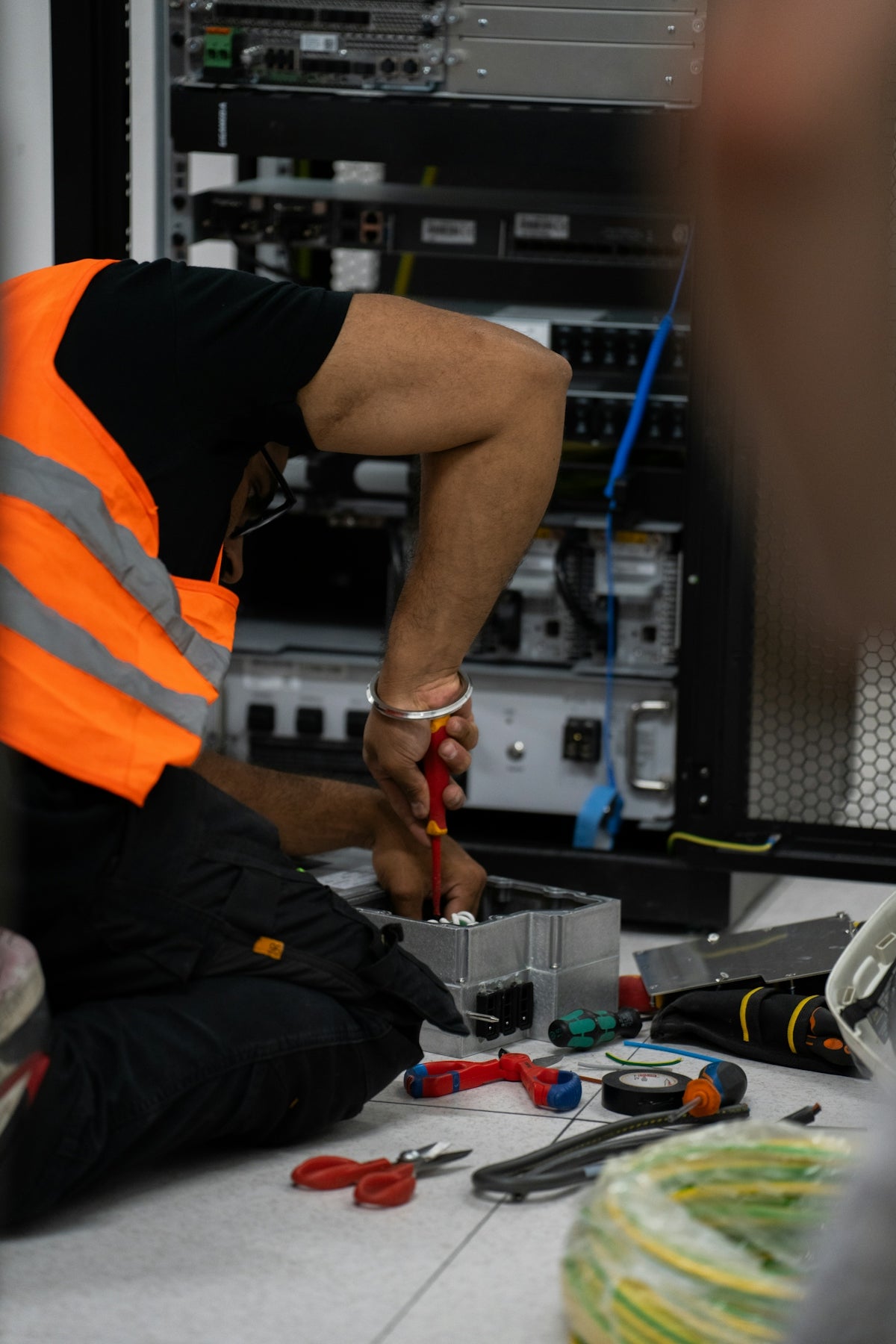 Technician working on network equipment with tools